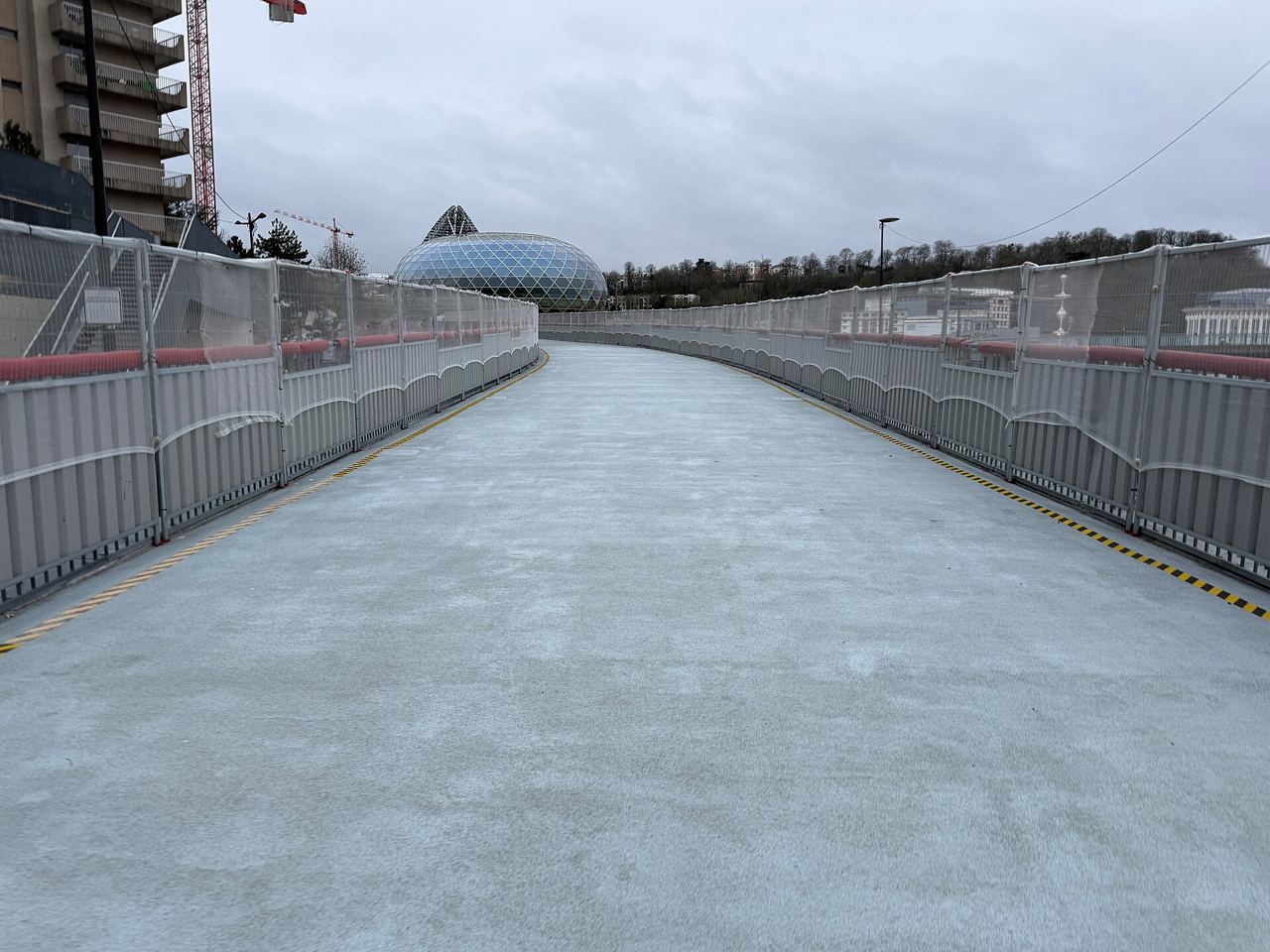 La passerelle nord de l'île Seguin à Boulogne-Billancourt, large tablier gris bordé de garde-corps, qui file vers le dôme de verre de La Seine Musicale.