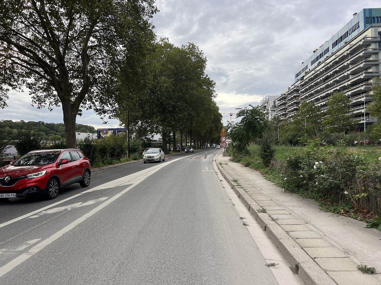 Le quai Georges-Gorse à Boulogne-Billancourt sous les platanes, une voie marquée d'un pictogramme vélo le long de la chaussée et des immeubles de bureaux à droite.